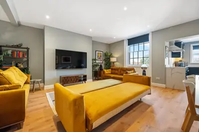 a bedroom with a yellow bed and a living room at Host & Stay - Upper Duke Street Apartment in Liverpool
