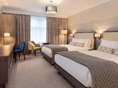 a hotel room with two beds and a desk at Mercure Blackburn Dunkenhalgh Hotel & Spa in Blackburn