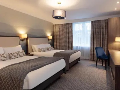 a hotel room with two beds and a desk at Mercure Blackburn Dunkenhalgh Hotel & Spa in Blackburn