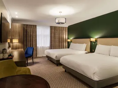 a hotel room with two beds and a chair at Mercure Blackburn Dunkenhalgh Hotel & Spa in Blackburn