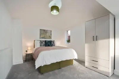 a white bedroom with a bed and a white cabinet at Modern 5BR Victorian Home in Liverpool in Knowsley