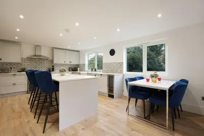 a kitchen with a white island and blue chairs at Modern 5BR Victorian Home in Liverpool in Knowsley