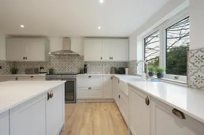a kitchen with white cabinets and a large window at Modern 5BR Victorian Home in Liverpool in Knowsley