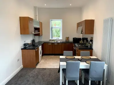 a kitchen with a table and chairs in a kitchen at New large 2 bedroom apartment with private parking in Lea Town