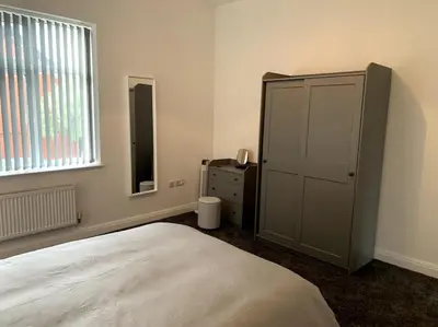 a bedroom with a bed and a dresser and a window at New large 2 bedroom apartment with private parking in Lea Town