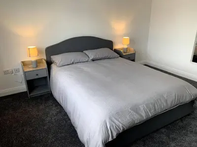 a bedroom with a large bed with two night stands at New large 2 bedroom apartment with private parking in Lea Town