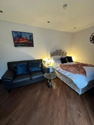 a bedroom with a bed and a leather couch at The Cottage Hideout in Upholland