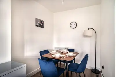 a dining room with a table and blue chairs at Spacious 2 Bed Apartment in Waterloo Liverpool in Waterloo