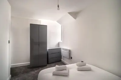 a white room with a bed and a black cabinet at Spacious 2 Bed Apartment in Waterloo Liverpool in Waterloo