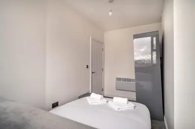 a white bedroom with two beds and a window at Spacious 2 Bed Apartment in Waterloo Liverpool in Waterloo