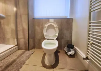 a bathroom with a toilet with a window and a tub at Kop View in Liverpool