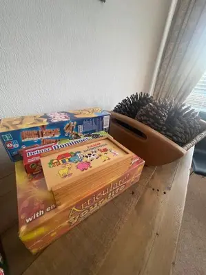 a pile of books on the floor next to a box of pine cones at Fylde Coast Stays - Home from Home in Freckleton