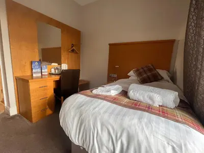 a bedroom with a bed and a desk with towels at King Alfred Hotel in Barrow in Furness
