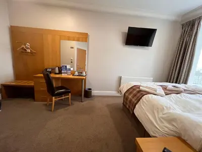 a hotel room with a bedroom with a desk and a bed at King Alfred Hotel in Barrow in Furness