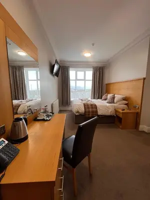 a room with a desk and a bedroom with a bed at King Alfred Hotel in Barrow in Furness