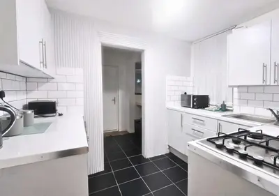 a kitchen with white cabinets and a black tile floor at Matchday Mile House Walk to Anfield sleeps 8 in Liverpool