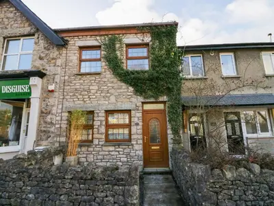 a stone house with a brown door and ivy at Time and Tide in Carnforth