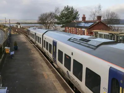a white train is stopped at a train station at Time and Tide in Carnforth