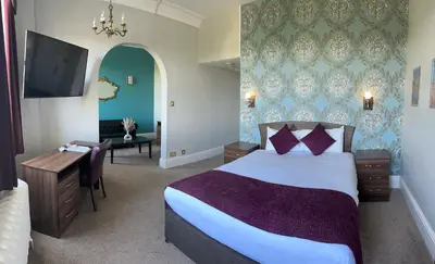 a bedroom with a bed and a desk and a television at Royal Clifton Hotel in Southport