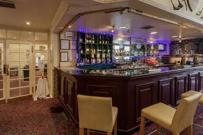 a bar with two chairs and a counter with drinks at Prince Of Wales Hotel in Southport