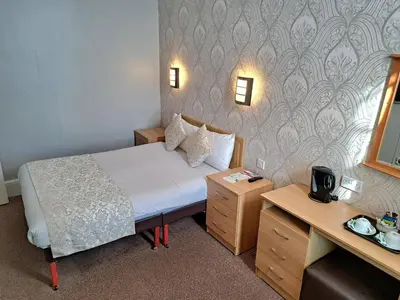 a small room with a bed and a desk at Prince Of Wales Hotel in Southport
