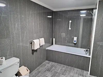 a bathroom with a shower and a toilet and a tub at Prince Of Wales Hotel in Southport