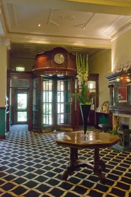 a lobby with a table and a clock on the wall at Prince Of Wales Hotel in Southport