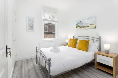a bedroom with a white bed with yellow pillows at Flatzy - Modern 3 Bedroom Home in City Centre in Liverpool