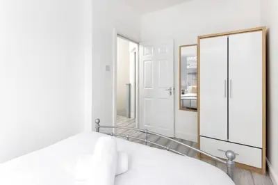 a white bedroom with a mirror and a bed at Flatzy - Modern 3 Bedroom Home in City Centre in Liverpool