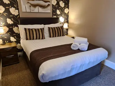 a bedroom with a bed with two towels on it at The Penkelie in Southport