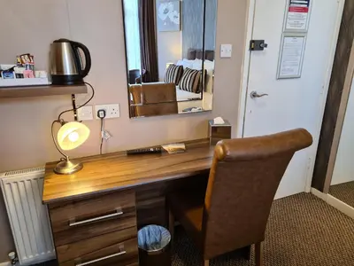 a desk with a lamp and a chair in a room at The Penkelie in Southport