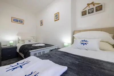 two beds in a bedroom with white walls at The Bay Cottage Hot Tub & Sauna Morecambe Bay in Morecambe
