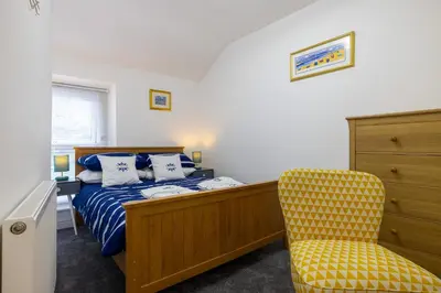 a bedroom with a bed and a yellow chair at The Bay Cottage Hot Tub & Sauna Morecambe Bay in Morecambe