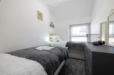 a bedroom with two beds and a mirror at The Bay Cottage Hot Tub & Sauna Morecambe Bay in Morecambe