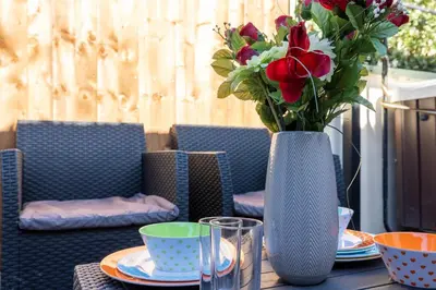 a table with a vase with a bouquet of flowers at The Bay Cottage Hot Tub & Sauna Morecambe Bay in Morecambe