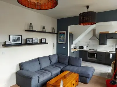 a living room with a blue couch and a kitchen at Large 2 Bedroom City Centre Apartment + Parking in Preston