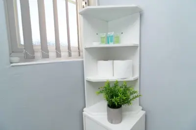 a bathroom with white shelves with towels and a plant at Central Liverpool Haven 3 bedroom House Private Parking in Liverpool
