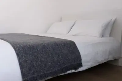 a white bed with a gray blanket on it at Stylish Double Room in City Centre - Shared Bathroom - Parking in Preston