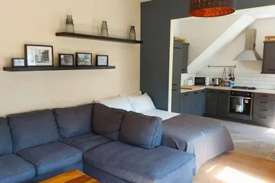 a living room with a blue couch and a kitchen at Large Studio Room in City Centre (Shared Bathroom) in Preston