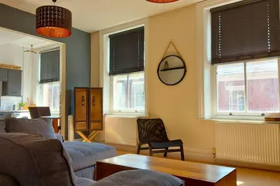 a living room with a couch and a table and windows at Large Studio Room in City Centre (Shared Bathroom) in Preston
