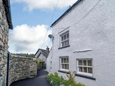 a white house with a stone wall next to a street at 3 Bed in Grange-over-sands oc-83368 in Cartmel