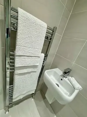 a white bathroom with a sink and towels at Entire Town House In Liverpool Marina in Liverpool