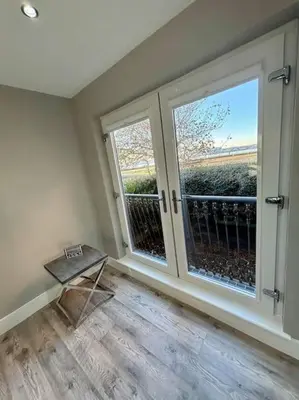an empty room with two large windows and a table at Entire Town House In Liverpool Marina in Liverpool