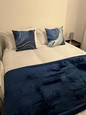 a bed with blue and white pillows on it at Princess Wigan House in Wigan