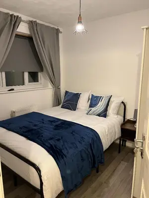 a bedroom with a large bed with blue and white sheets at Princess Wigan House in Wigan