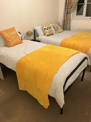 two beds with orange and white sheets in a room at Princess Wigan House in Wigan
