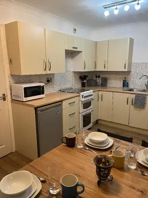 a kitchen with a wooden table with plates on it at Princess Wigan House in Wigan