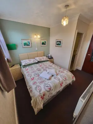 a bedroom with a large bed with a flowered blanket at The Arabella in Blackpool