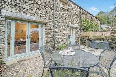 a patio with a table and chairs in front of a building at 2 Bed in Ulverston oc-sz013 in Haverthwaite