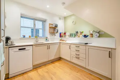 a large kitchen with white cabinets and a window at 2 Bed in Ulverston oc-sz013 in Haverthwaite